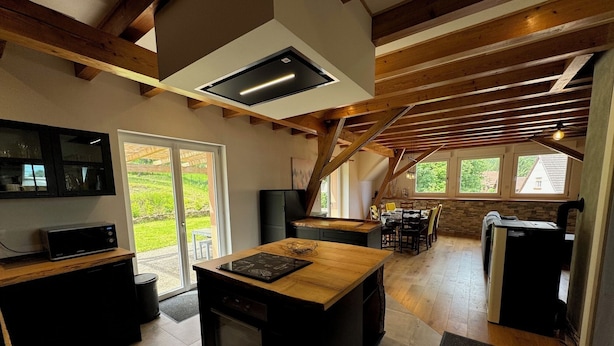 A modern kitchen with a central island, built-in appliances, and a large window overlooking a garden. - L'Echappée Verte, your nature cocoon in the heart of Alsace Verte (Dambach)