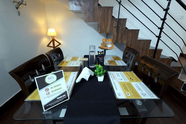 A dining area with a table set for four, a small potted plant, and a sign indicating no smoking and no drinking.