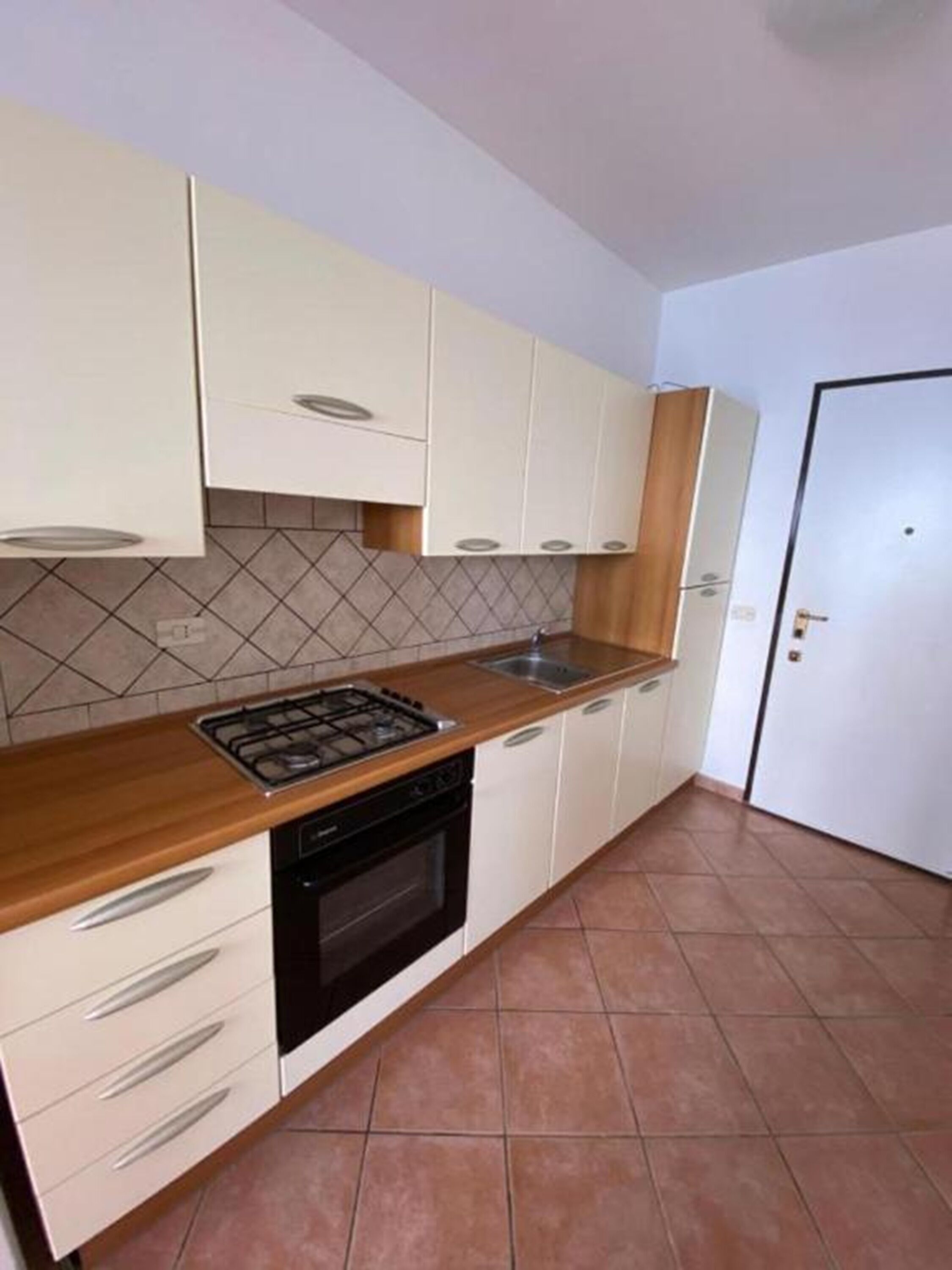 A kitchen with white cabinets, a wooden countertop, a stove, and a sink.