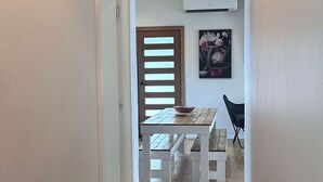 A narrow hallway leading to a dining area with a wooden table and a bowl.
