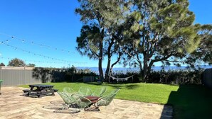 A backyard with a picnic table, chairs, and a hammock.