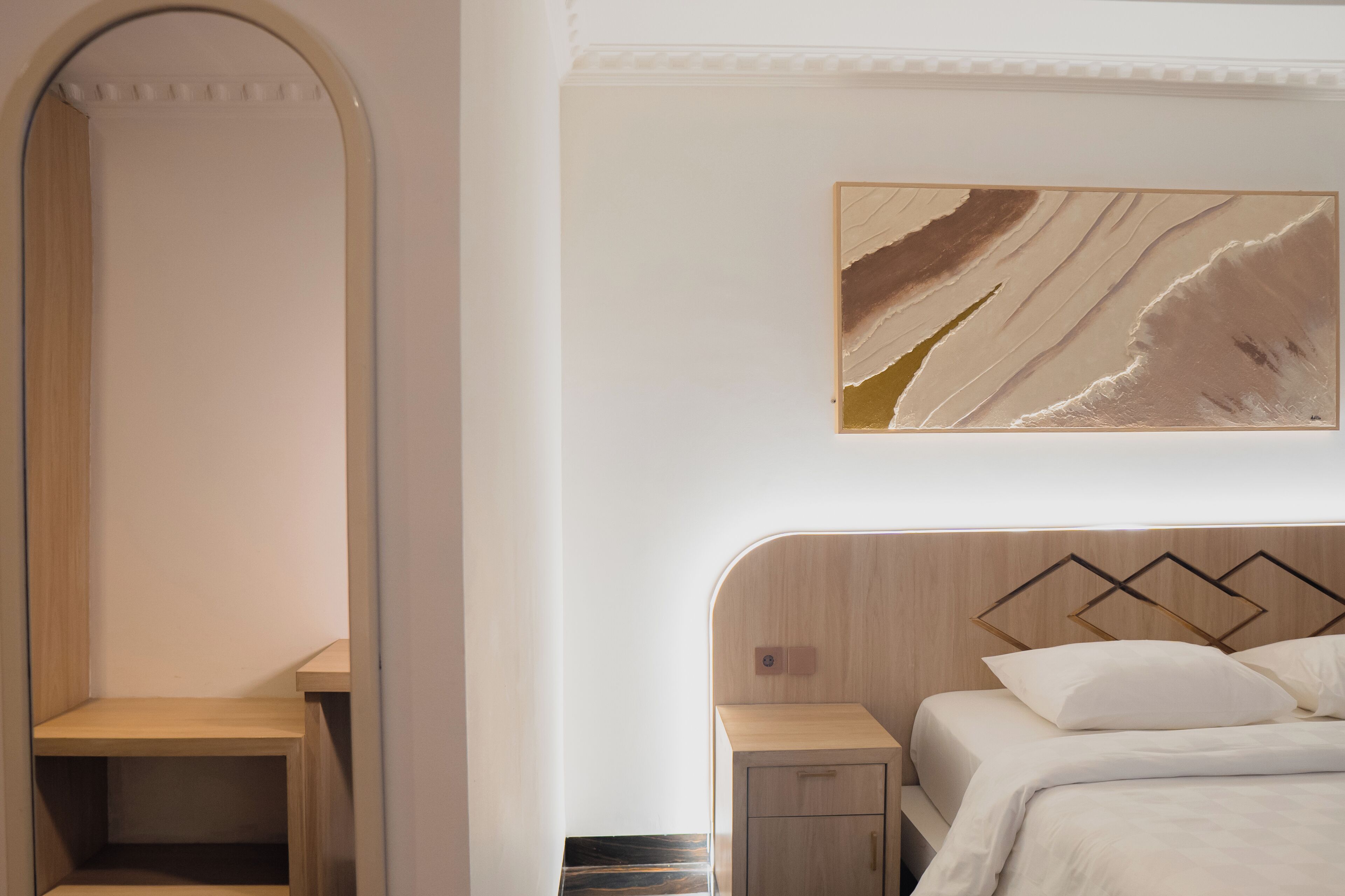 Een moderne slaapkamer met een bed, nachtkastjes en een kunstwerk aan de muur.