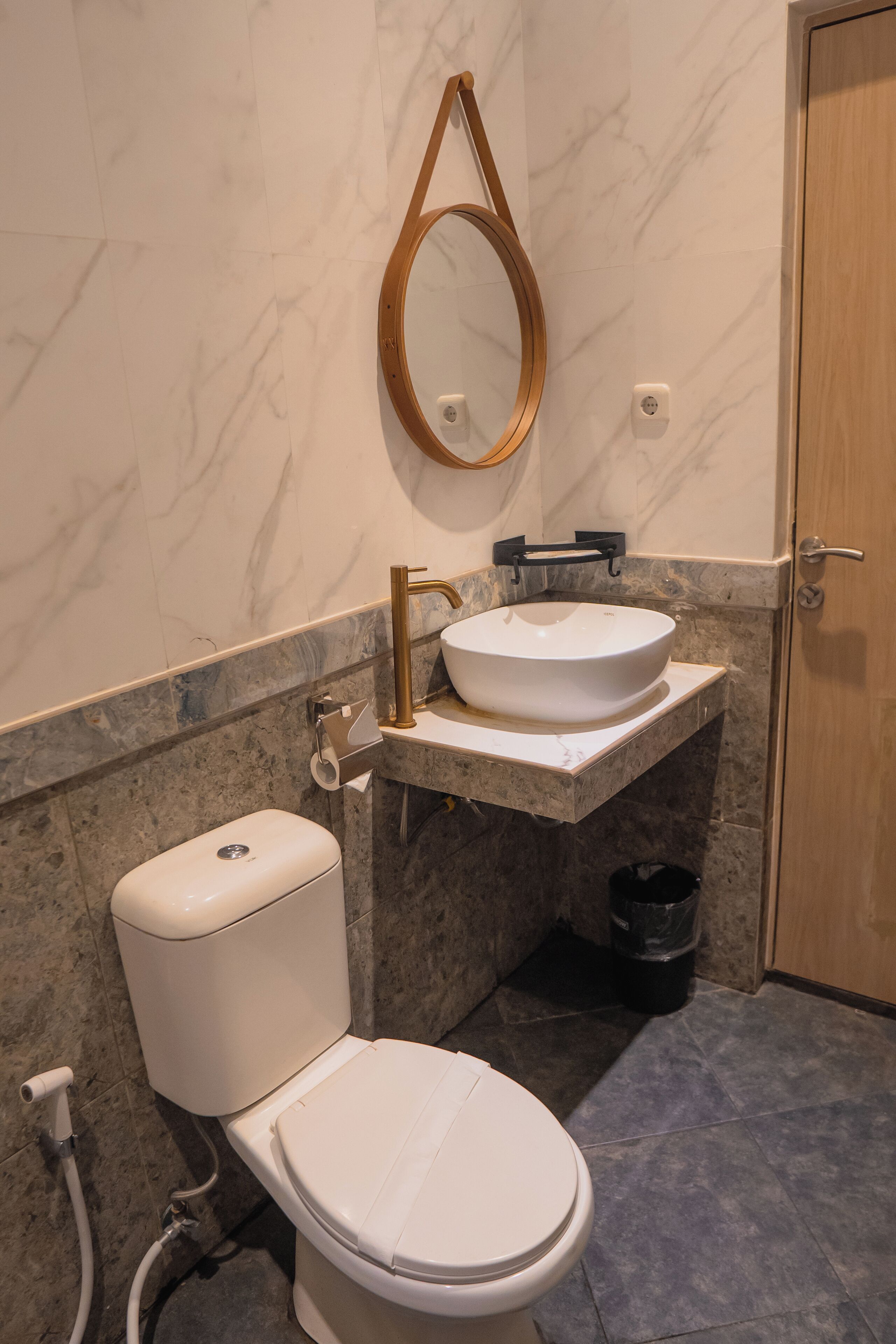 A bathroom with a toilet, sink, and mirror.