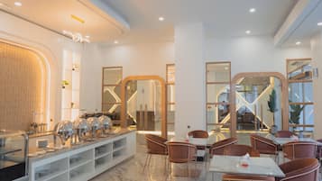 A modern hotel dining area with a buffet, seating, and a view of the interior.