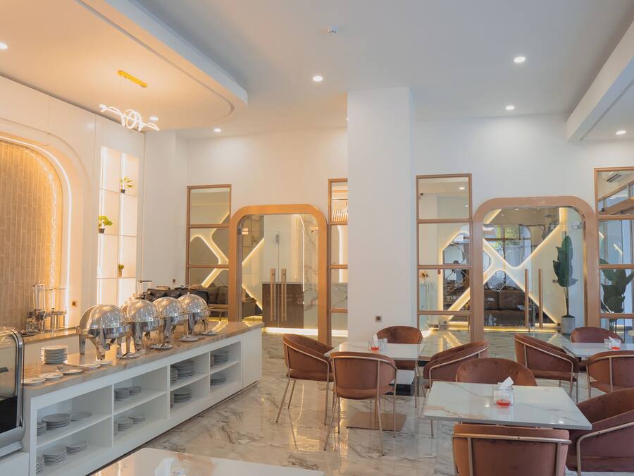 A modern hotel dining area with a buffet, seating, and a view of the interior.