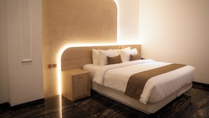 Een moderne hotelkamer met een groot bed, een nachtkastje en een in het hoofdeinde geïntegreerde verlichting.