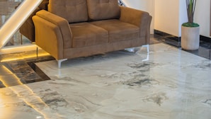 Een moderne lobby met een geometrisch wandontwerp, een bruine bank en een grote potplant.