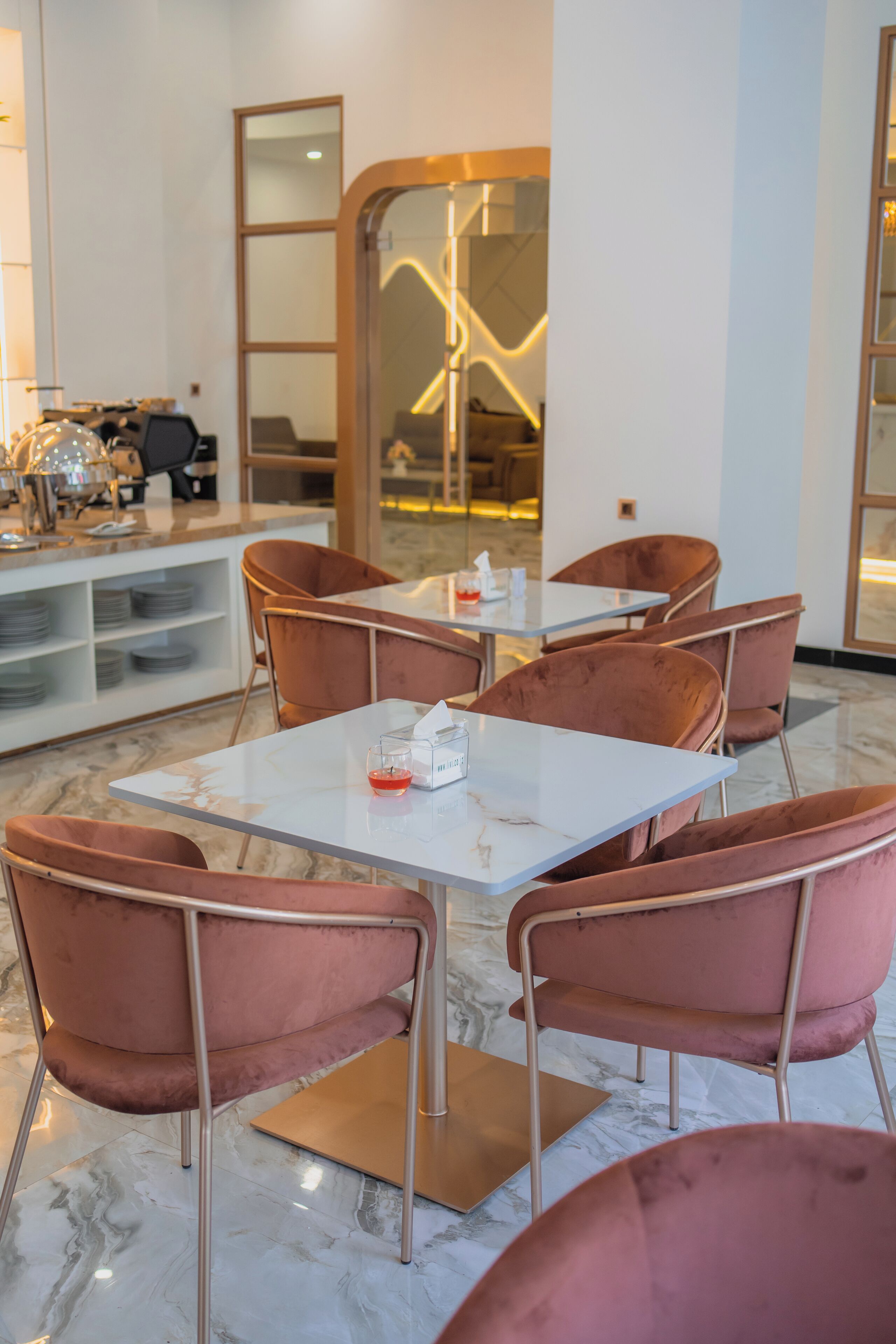 Un comedor con una mesa blanca, seis sillas rosas y una lámpara de techo moderna.