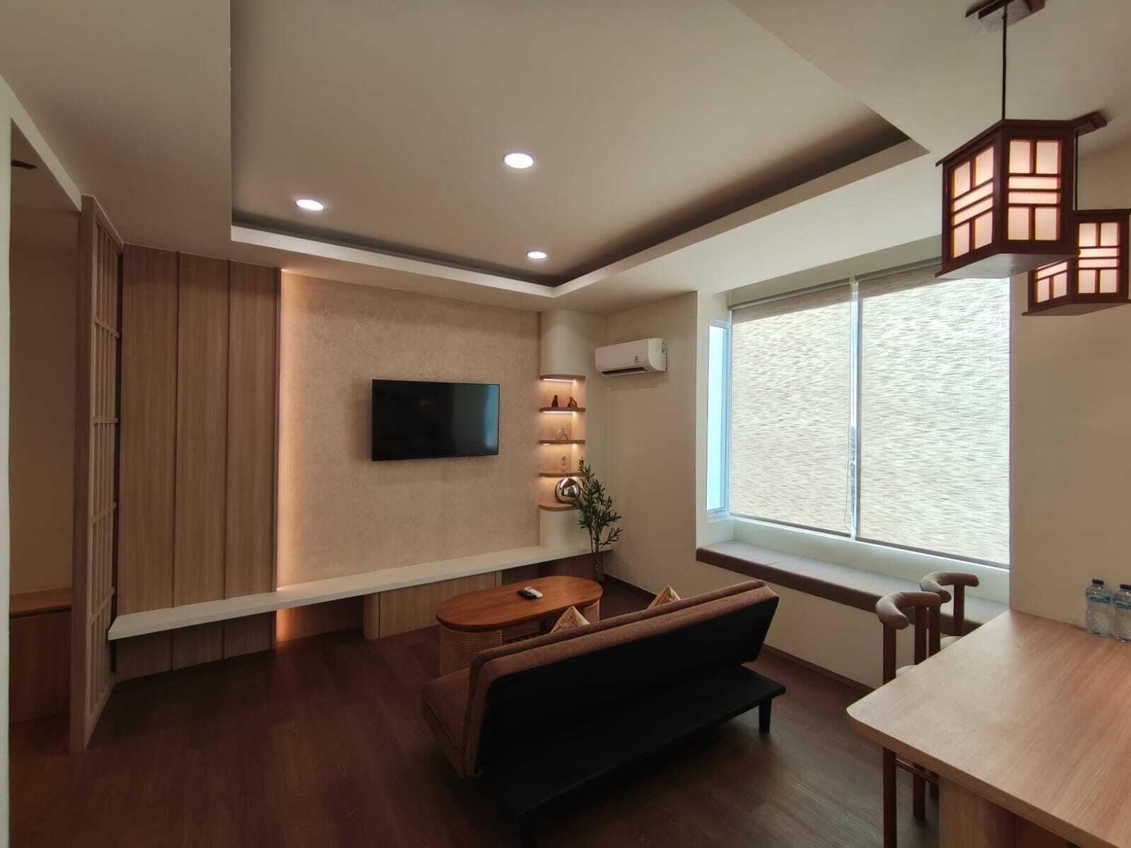Una sala de estar moderna con un televisor de pantalla plana, un sofá, una mesa de comedor y un ventanal grande.