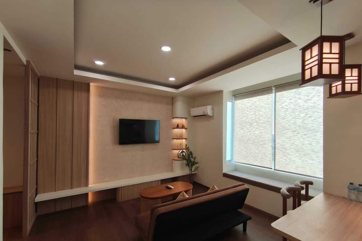 Una sala de estar moderna con un televisor de pantalla plana, un sofá, una mesa de comedor y un ventanal grande.