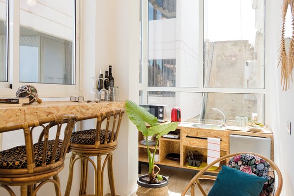 Una cocina moderna con zona de comedor, ventanas amplias y una planta en maceta.