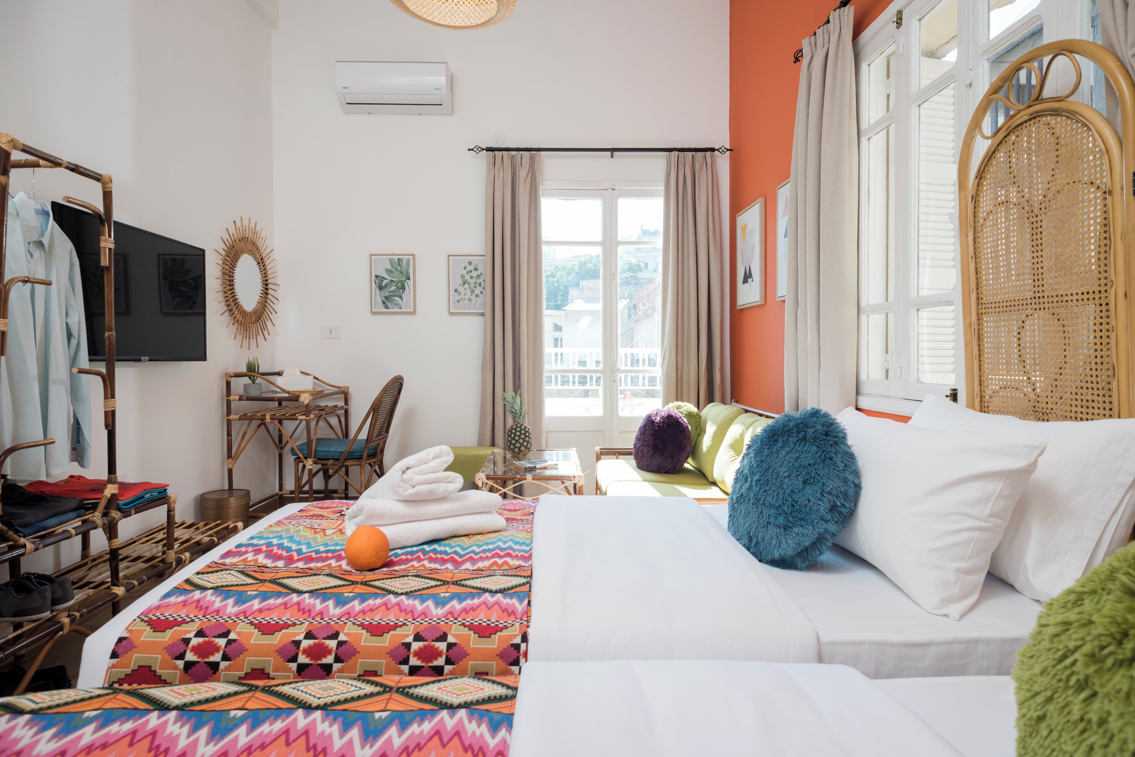 Een hotelkamer met een bed, een stoel, een klein tafeltje en een raam met gordijnen.