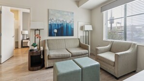 A modern living room with a sofa, two armchairs, a coffee table, and a painting on the wall.