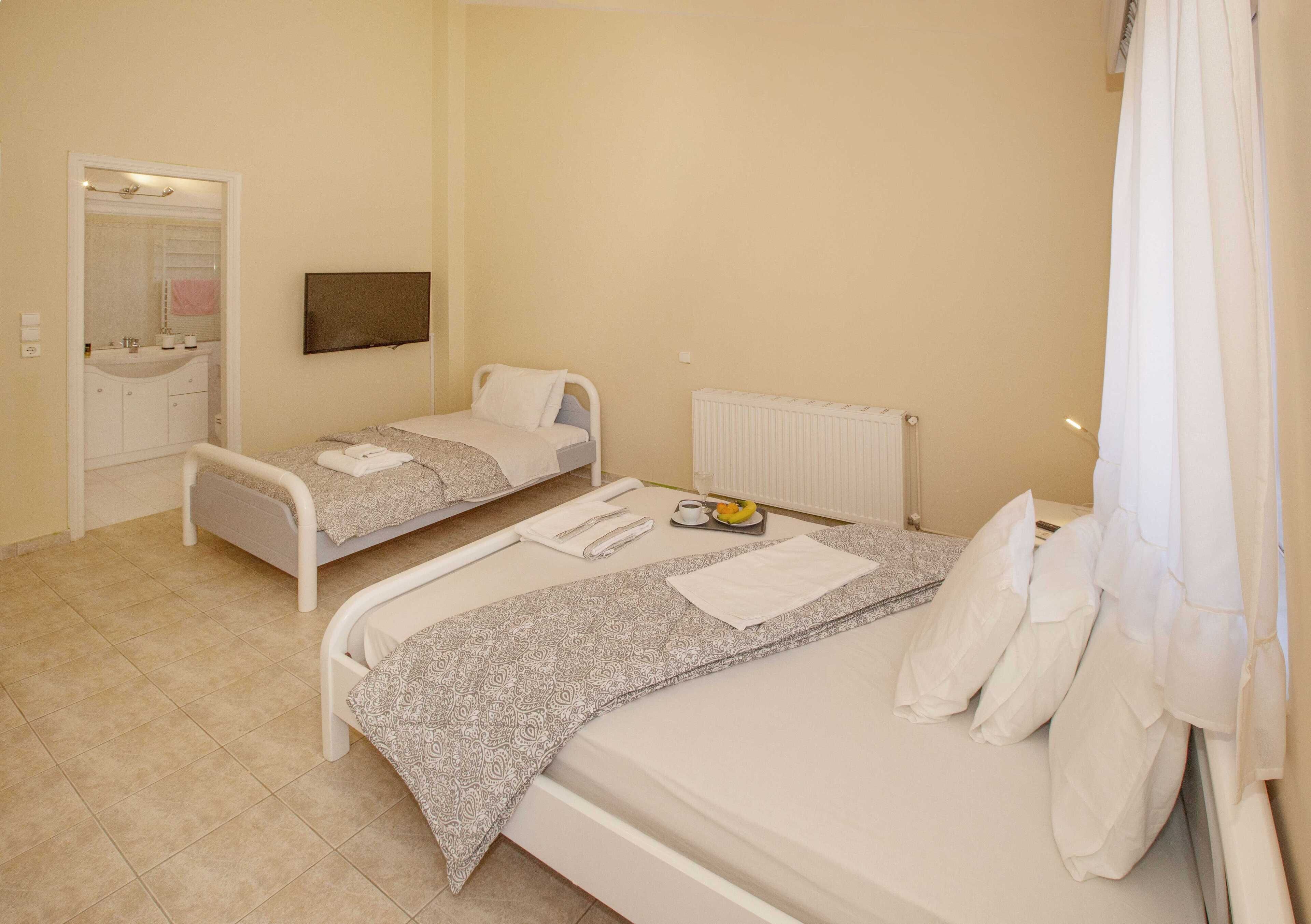 A hotel room with two beds, a bathroom, and a TV.