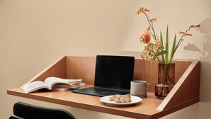 A workspace with a laptop, an open book, a mug, a plate with cookies, and a vase with flowers. - Bob W Stockholm Norrmalm (Stockholm)