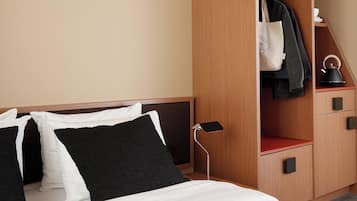 Een hotelkamer met een bed, een kast en een kleine tafel met een waterkoker.
