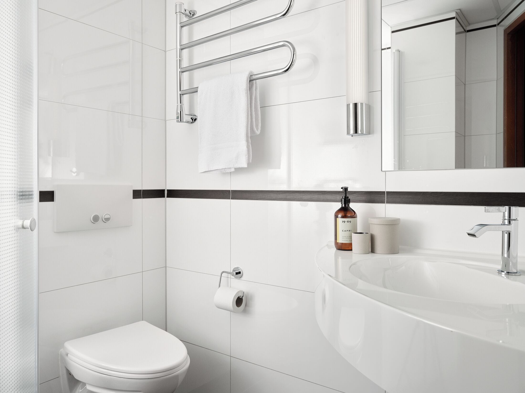 A modern bathroom with a white toilet, a sink, and a towel rack.