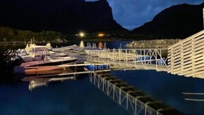 A marina with boats docked, a wooden pier, and mountains in the background. - Fjordcamp AS (Straumsjøen)