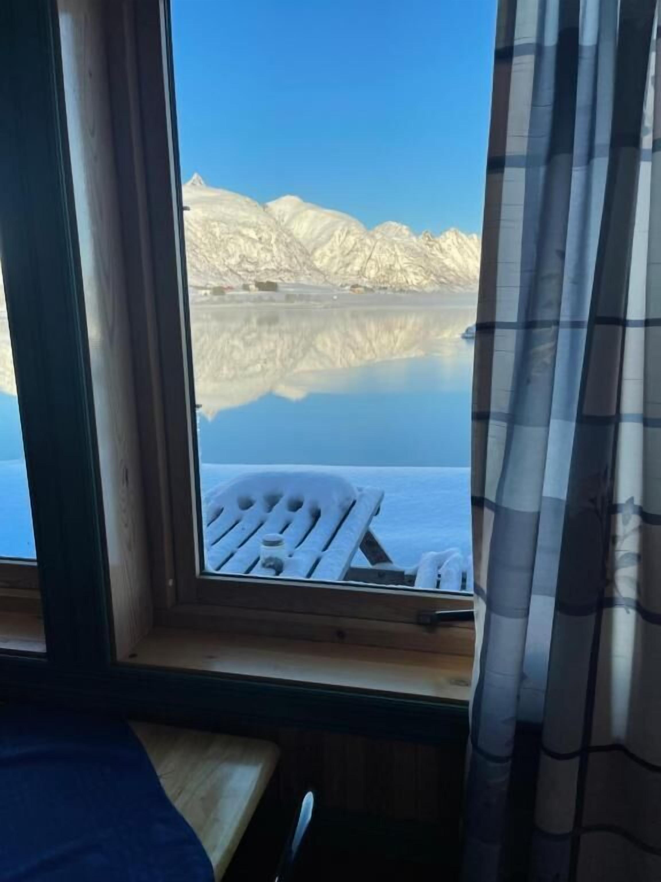 Una habitación con ventana que da a un paisaje nevado y un lago.