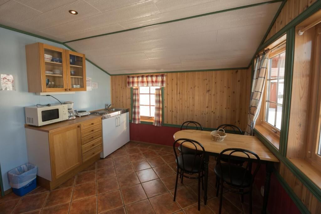 A compact kitchen with wooden cabinets, a microwave, and a dining table with chairs.