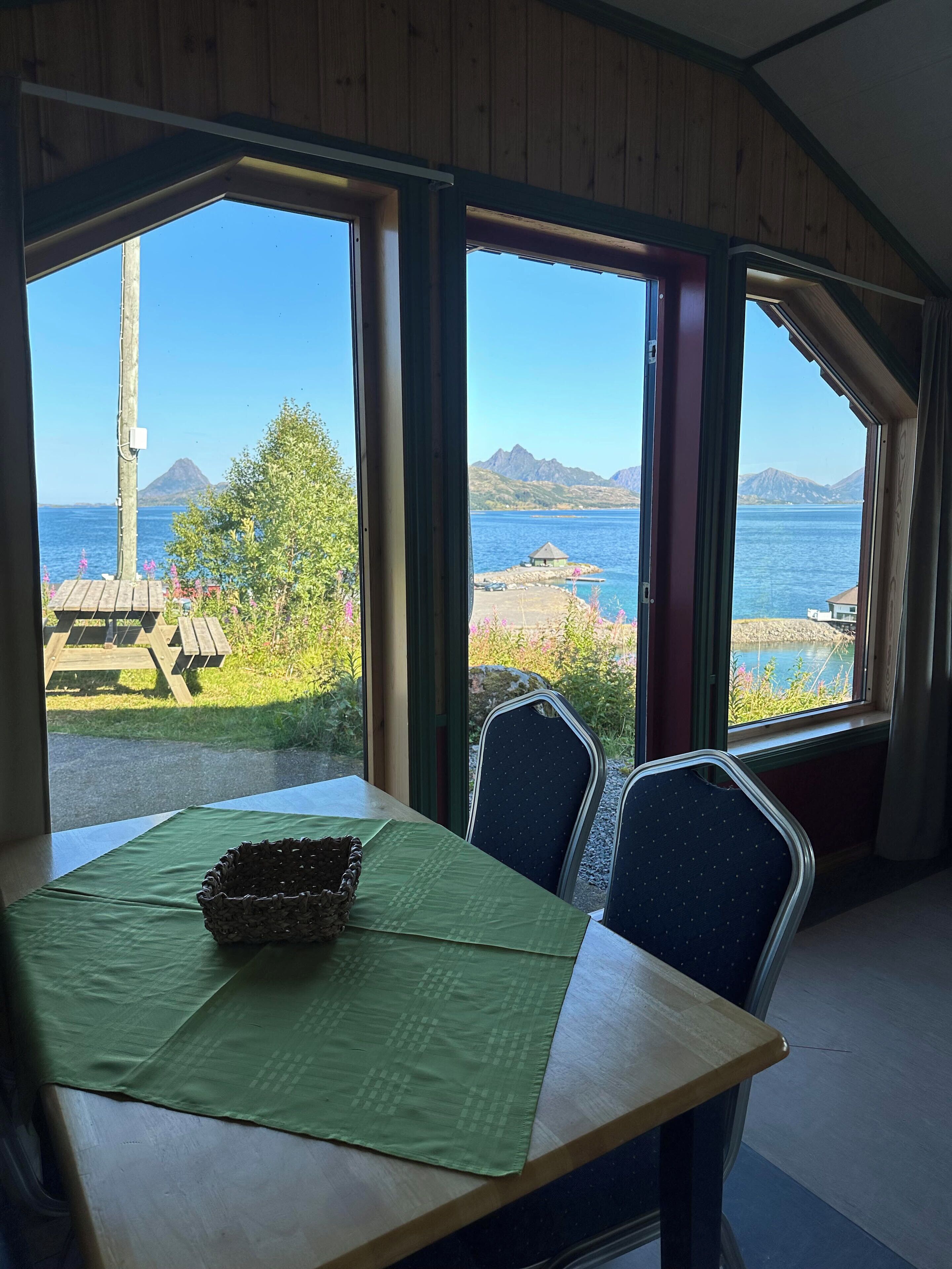 A dining area with a table, chairs, and a view of a lake and mountains.
