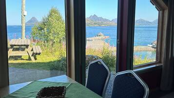 A dining area with a table, chairs, and a view of a lake and mountains.