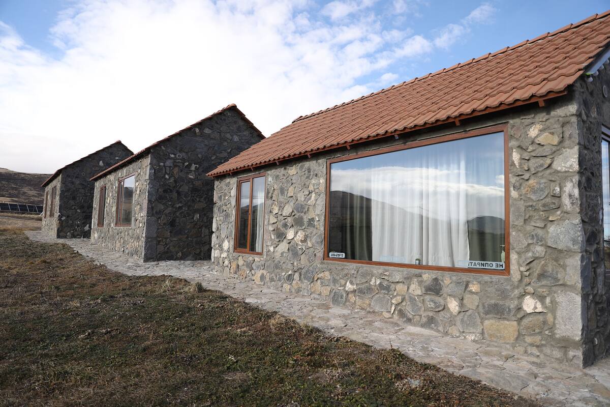 A row of stone buildings with tiled roofs and large windows.