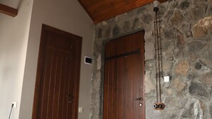 A bedroom with a wooden ceiling, stone walls, a wooden door, and a bed with a green blanket. - The Ranch (Goris)