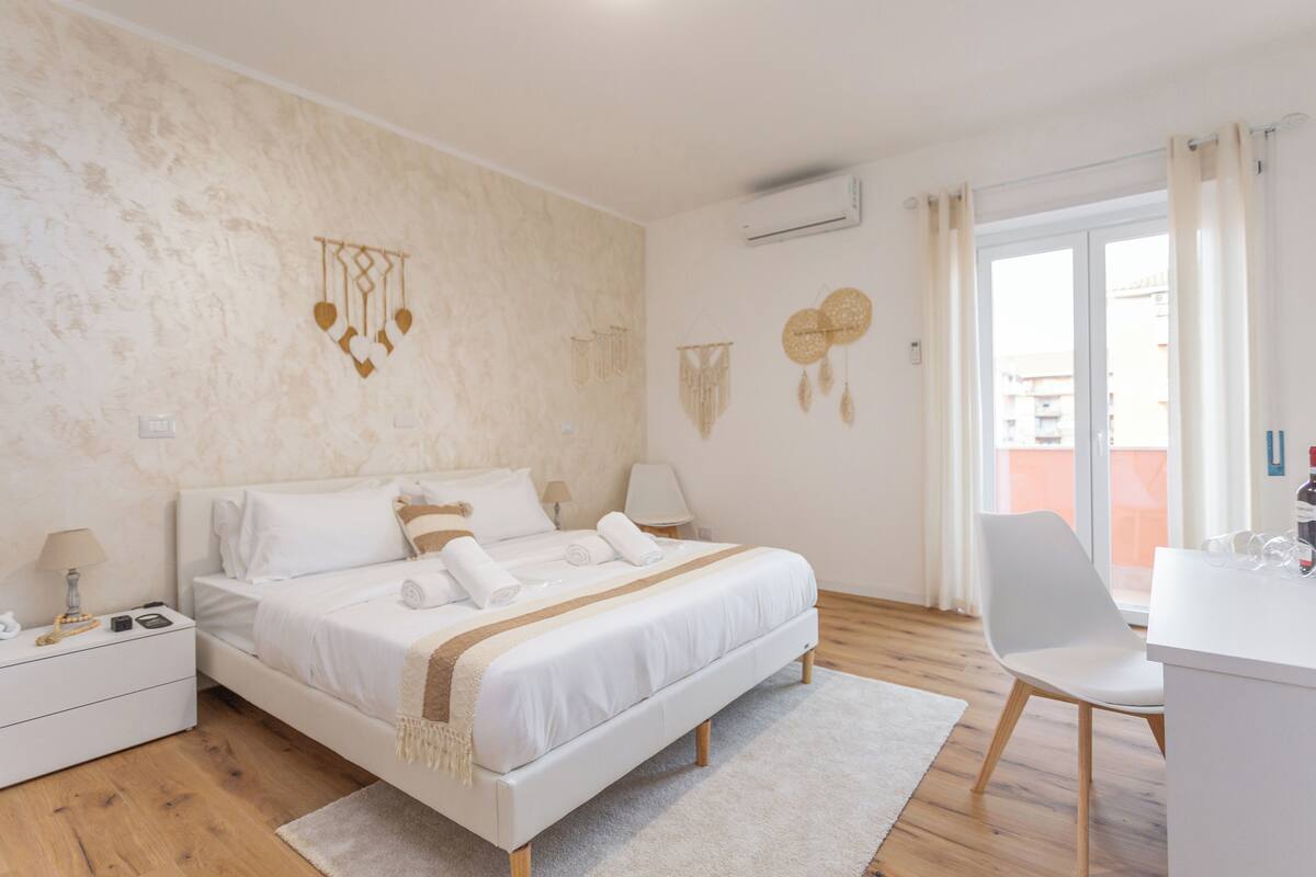 A bedroom with a bed, bedside tables, a desk, and a chair.