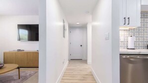 A narrow hallway with a wooden floor, a dining area with a table and chairs, and a kitchen area with cabinets and a dishwasher. - Cheery Lynn I Cozy Luxe Escape (Scottsdale)