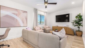 A modern living room with a sofa, armchairs, a TV, and a ceiling fan. - Cheery Lynn I Cozy Luxe Escape (Scottsdale)