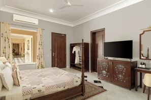 A bedroom with a bed, a wardrobe, a television, and a bathroom visible through an open door.