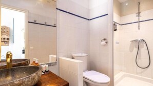 A bathroom with a large stone basin, a toilet, and a shower area. - Le Miroir d'André séjour bonheur au cœur de Cannes (Cannes)