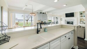 Een moderne keuken met een groot eiland, witte kastjes en uitzicht op de omgeving.