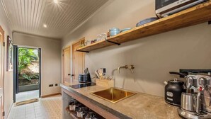 Une cuisine moderne dotée d’un évier encastré, d’étagères en bois et d’une machine à café.
