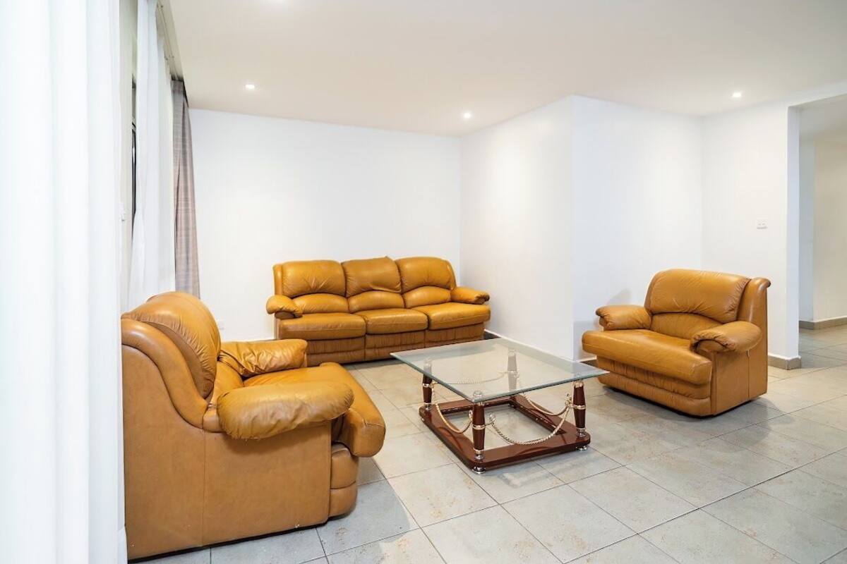 A living room with three leather sofas and a glass coffee table.