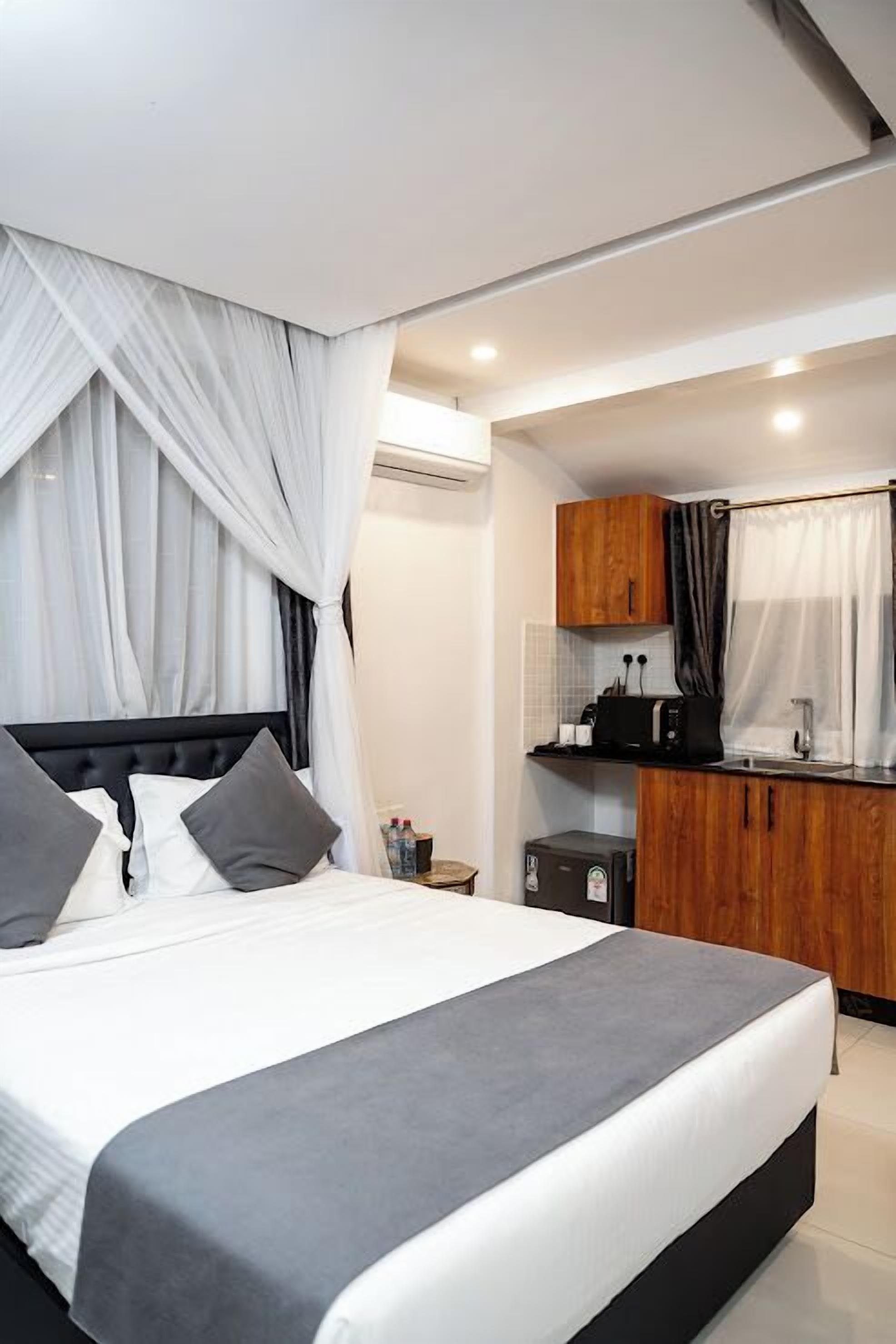 Un dormitorio moderno con una cama grande, una kitchenette pequeña y un baño.