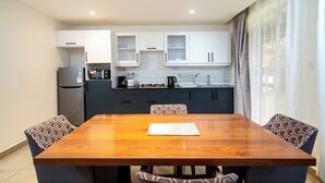 Eine moderne Küche mit weißen Schränken, einem eingebauten Ofen und einem Essbereich mit einem Holztisch und gemusterten Stühlen.