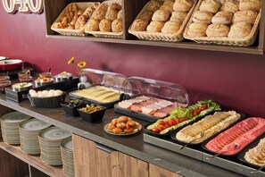 A buffet with various food items including bread, cheese, and salads. - Numa Hamburg St Georg (Hamburg)