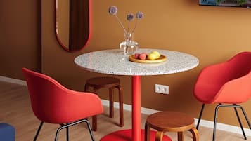 A round table with a red base, surrounded by two red chairs and a stool.