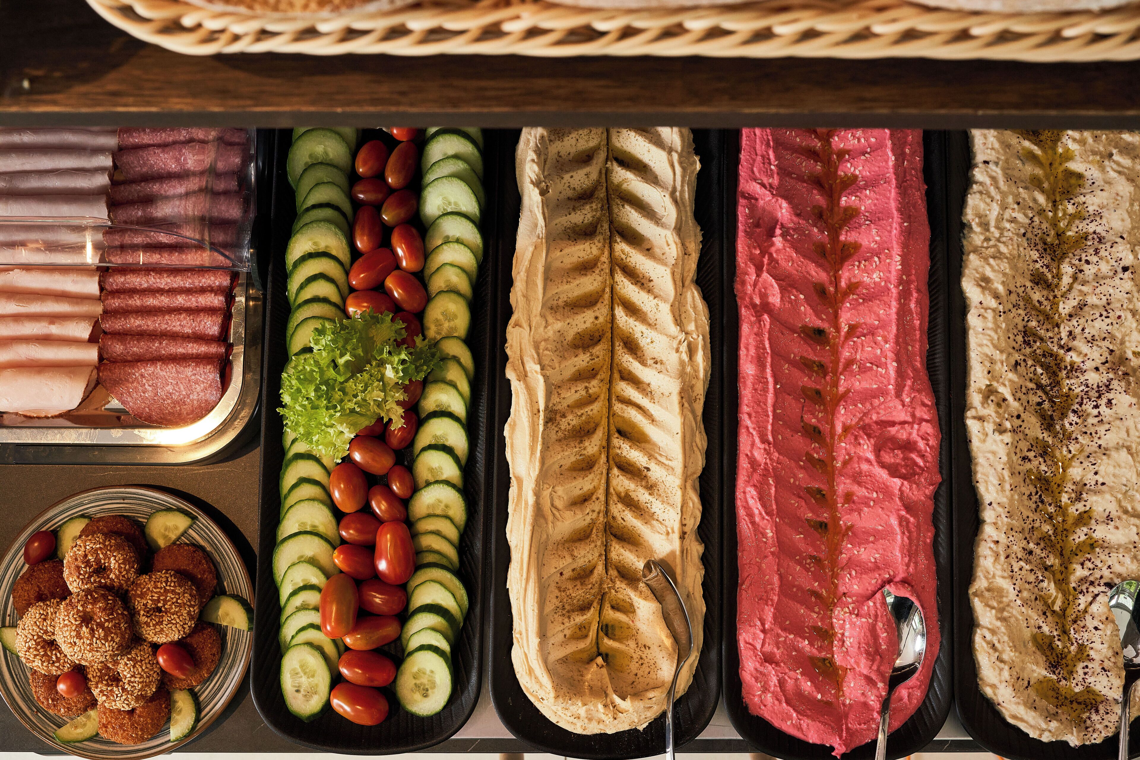 A variety of food items including sliced cucumbers, tomatoes, and meat, arranged in a tray.