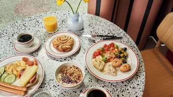 Et rundt bord med forskellige morgenmadsretter, herunder æg, ristet brød og en tallerken med grøntsager.