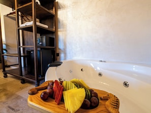A wooden fruit platter on a floor with a white bathtub in the background. - My Cappadocia Stone House (Nevsehir)