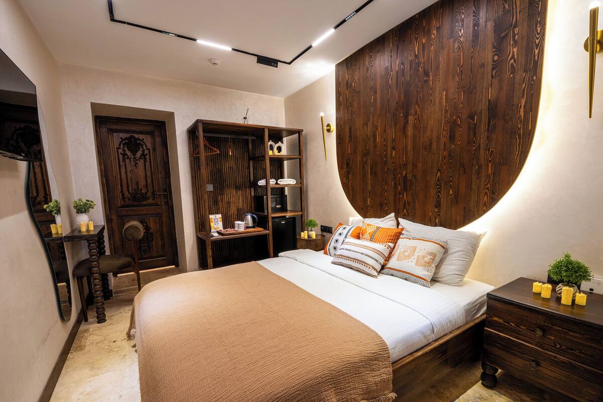 Un dormitorio con cama, mesita de noche, cómoda y armario de madera.