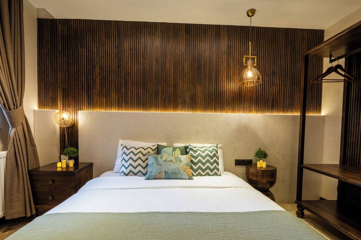 Un dormitorio moderno con una cama grande, una mesita de noche con lámpara, una lámpara colgante y un armario.