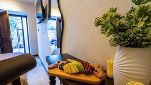 Uma mesa de madeira com uma travessa de frutas, um vaso de planta e uma vela.