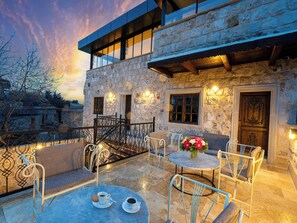 A stone building with a balcony, outdoor seating, and a view of the surrounding area. - My Cappadocia Stone House (Nevsehir)