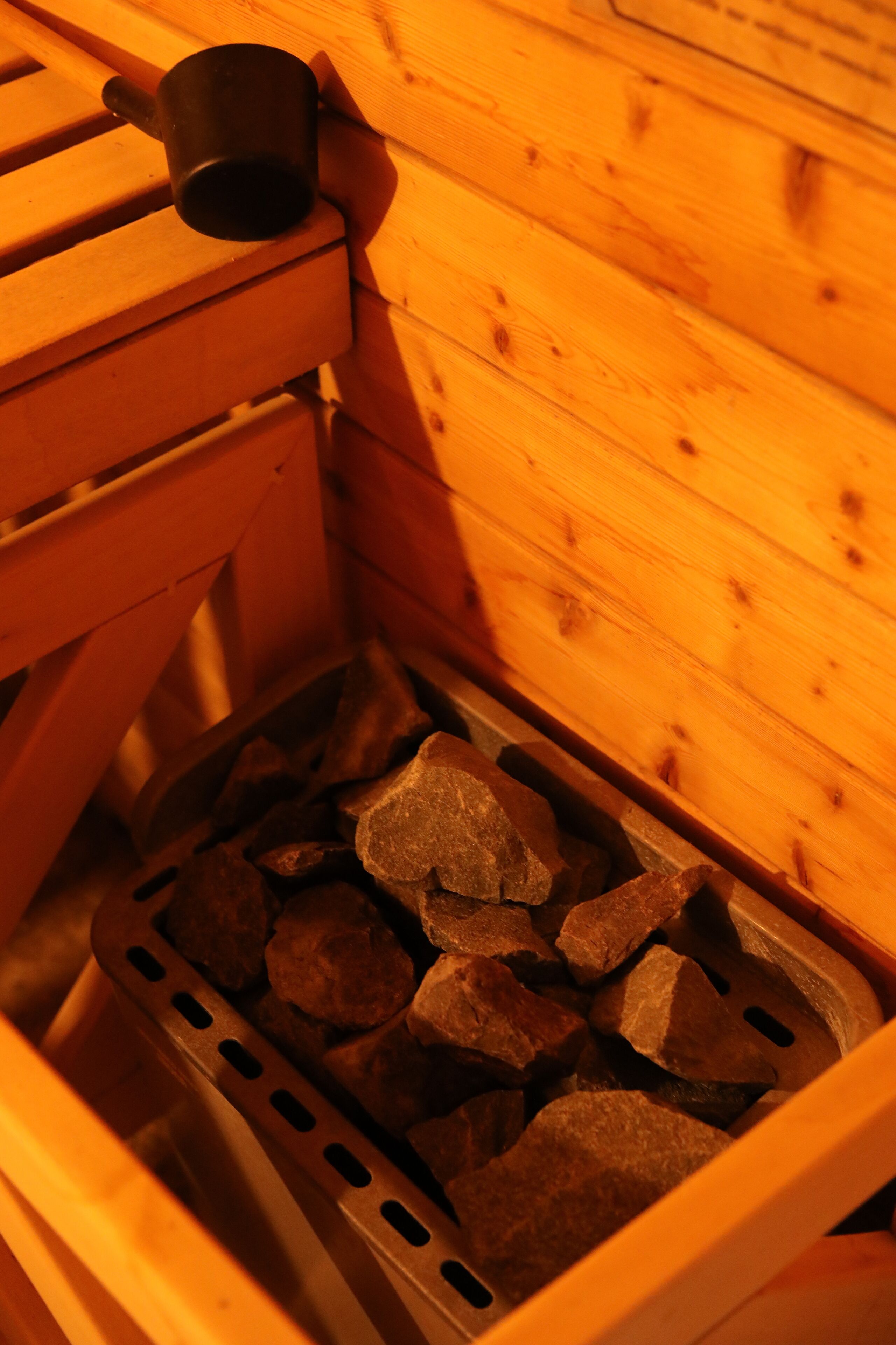 A wooden bench with a black mug on it and a metal tray filled with charcoal pieces.