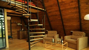 A cozy loft with a wooden interior, a spiral staircase, a sofa, and a coffee table with glasses and a bottle. - Panorama Sormoni (Tsqaltubo)