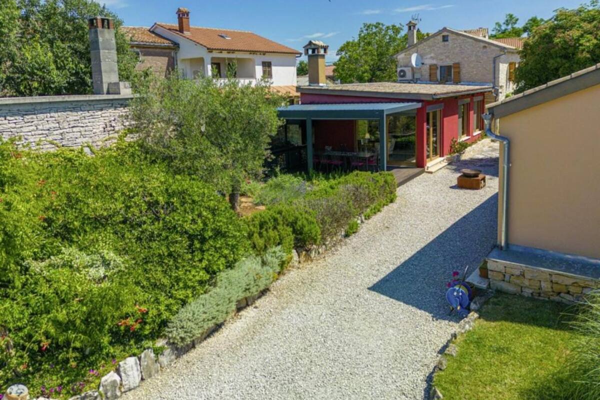 A residential property with a gravel driveway, a covered outdoor seating area, and a stone wall.
